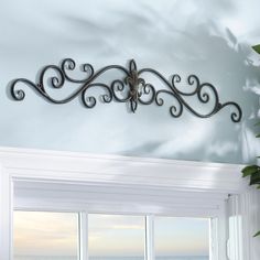 a metal wall hanging over a window next to a potted plant