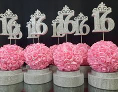 there are pink flowers in vases with silver numbers on them and one is for the number 16