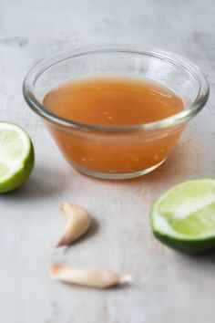 a glass bowl filled with liquid next to sliced limes