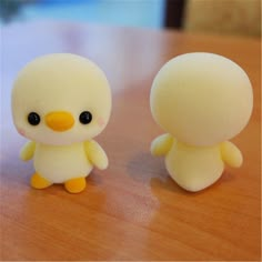 two small yellow and white toys sitting on top of a wooden table next to each other