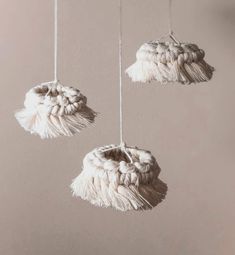 three white tasselled objects hanging from strings