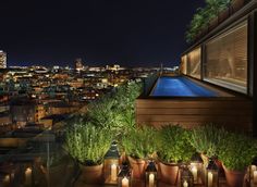 a rooftop with potted plants and candles lite up at night in front of the city lights