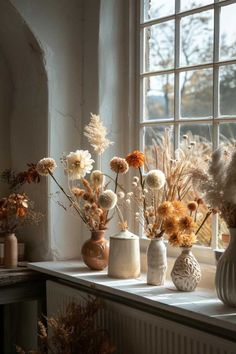 several vases filled with different types of flowers on a window sill next to a window