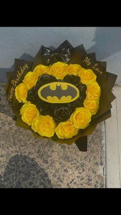 a batman cake with yellow roses in the shape of a wreath