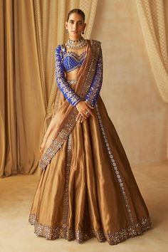 Copper shimmer lehenga with real hand cut mirror work. Comes with royal blue embroidered sweetheart neck blouse and dupatta.
Component: 3
Pattern: Embroidered
Type Of Work: Mirror Work
Neckline: Sweetheart
Sleeve Type: Full
Fabric: Lehenga and Dupatta: Shimmer Organza, Blouse: Georgette, Lining: Silk Blend
Color: Brown
Other Details: 
Potlis on neckline
Sheer dupatta with embroidered borders
Back tie-up with multi tassels
Occasion: Wedding - Aza Fashions Royal Indian Outfits, Copper Lehenga, Brown Lehenga, Shimmer Lehenga, Lehenga Ideas, Vani Vats, Sheer Dupatta, Langa Voni, Mirror Work Lehenga