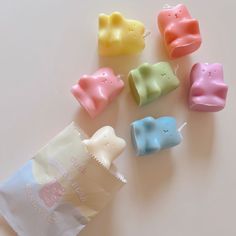 small candy candies in different colors and shapes on a white surface with a bag next to them