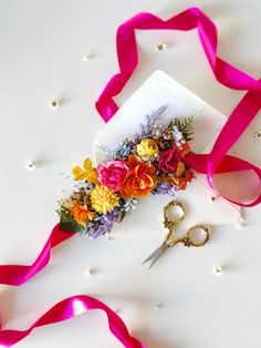 scissors, ribbon and flowers on a white surface with pearls in the backround