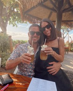 a man and woman holding drinks at an outdoor table