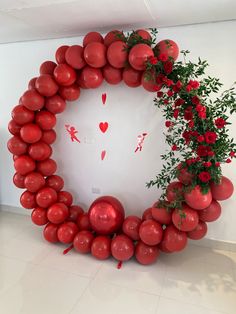 a large balloon wreath with red flowers and greenery