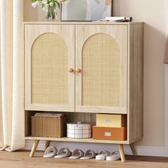 a wooden cabinet with two doors and baskets on the bottom shelf next to a window