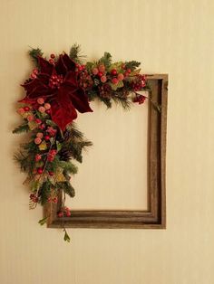 a christmas wreath hanging on the wall next to a wooden frame with holly and poinsettis