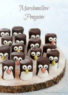 there are many penguins made out of marshmallows on top of a wooden board