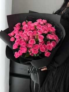 a woman holding a bouquet of pink roses