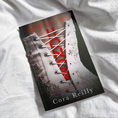 a book laying on top of a bed next to a white sheet with red writing