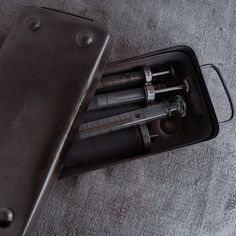 an open metal case with two tools inside