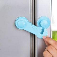 a hand is holding the handle to a refrigerator door knob that has a blue latch on it