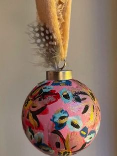 a pink ornament with feathers hanging from it's side and on top