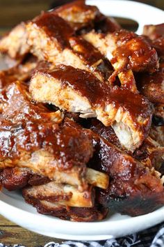 ribs covered in bbq sauce on a white plate with a black and white napkin