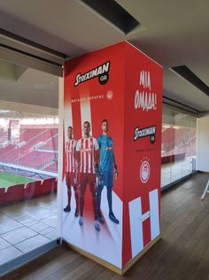 a large red and white box with two men standing in front of it on a wooden floor