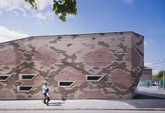 a woman walking past a brick building with windows