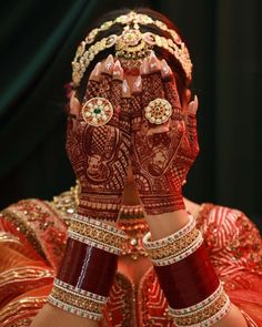 a woman with her hands covered in hendi and jewelry, showing the intricate designs on her hands