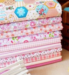 a stack of colorful fabrics sitting on top of a table next to flowers and boxes