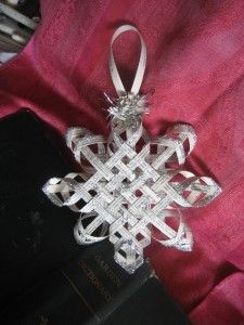 a snowflake ornament sitting on top of a red cloth next to a book