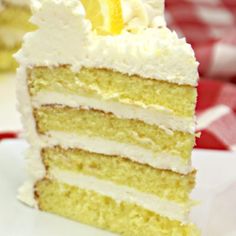 a slice of cake with white frosting and a lemon wedge on the top is sitting on a plate