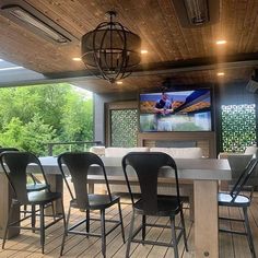 a dining room table with chairs and a television on the wall