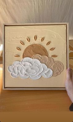 someone is holding up a painting with clouds and sun