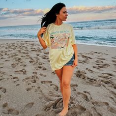 a woman is walking on the beach in shorts and a t - shirt that says once beach