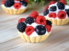 three small cupcakes with berries and blackberries on top