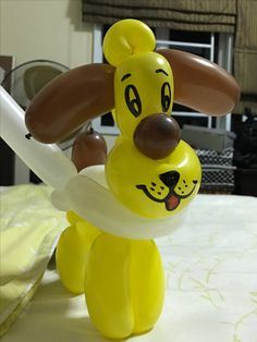 a balloon dog holding a white frisbee on top of a bed