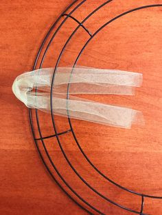 a close up of a clock on a wooden surface with two white ribbons attached to it