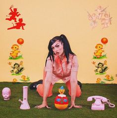 a woman sitting on the ground in front of various toys and decorations, including telephones