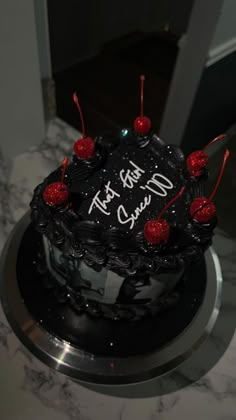 a black cake with red cherries on it