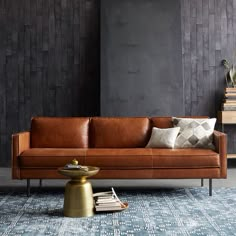 a brown leather couch sitting on top of a blue rug next to a wooden table