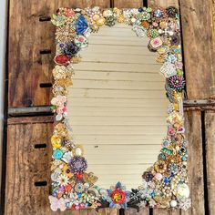 a mirror that is sitting on top of a wooden table with buttons and other things around it