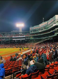 a baseball stadium filled with lots of people sitting in the bleachers at night