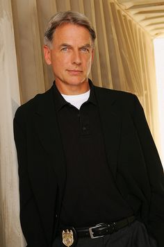 a man wearing a police uniform standing in front of a curtain