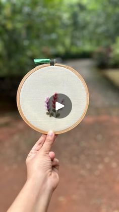 someone is holding up a small embroidery project with an arrow in it's center