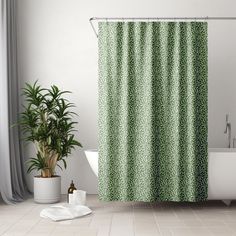 a bathroom with a green shower curtain next to a white bath tub and potted plant