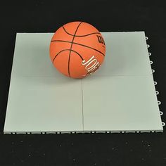 an orange basketball sitting on top of a piece of white paper next to a spiral notebook