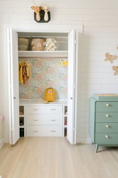 a white closet with drawers and clothes hanging on the wall