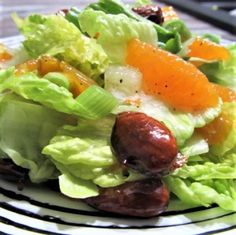 a salad with lettuce, carrots and other vegetables on a black and white plate