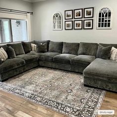 a large sectional couch sitting on top of a rug in a living room next to a window