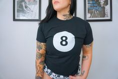 Embrace your inner downtown girl with this Angelcore Magic 8 Ball Billiards Shirt, a whimsical blend of Y2K vibes and balletcore flair. This Coquette Shirt is the epitome of 90s nostalgia reimagined for the modern teenage girl, making it a perfect gift for those with a penchant for kitsch fashion. This nostalgic 90s aesthetic T-Shirt features a retro lucky 8 ball design that adds a touch of charm to any outfit. The crop top silhouette elevates the overall look, ideal for creating trendy ensemble Trendy Fitted Pre-shrunk Shirt, Fitted Band Merch Tops With Front Print, Cotton Short Sleeve Shirt With Number Print, Retro Fitted Shirt With Screen Print, Cotton Number Print Top For Streetwear, Short Sleeve Cotton Shirt With Number Print, Retro Fitted Top, Retro Fitted Pre-shrunk Top, Fitted Grunge Tops With Graphic Design