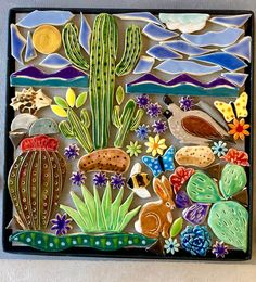 a decorative tile with cactus, flowers and other things in the shape of a desert scene