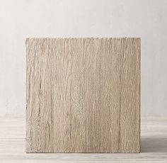 a square wooden block sitting on top of a white wood floor next to a wall