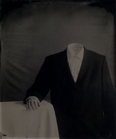 an old photo of a man in a tuxedo and bow tie holding a table cloth